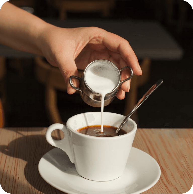 Milk being poured into black coffee