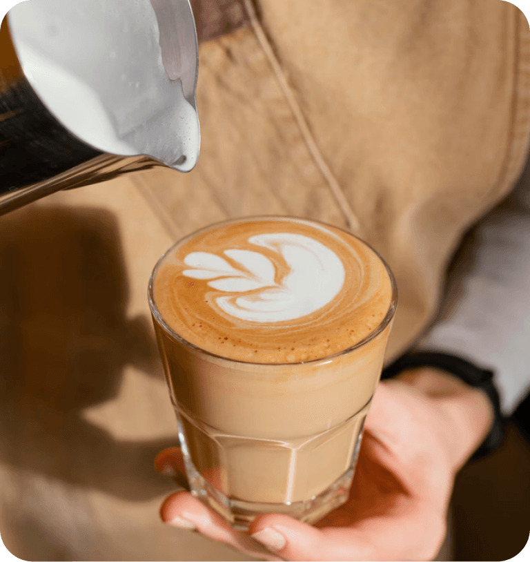 Barista pouring milk into latte with art